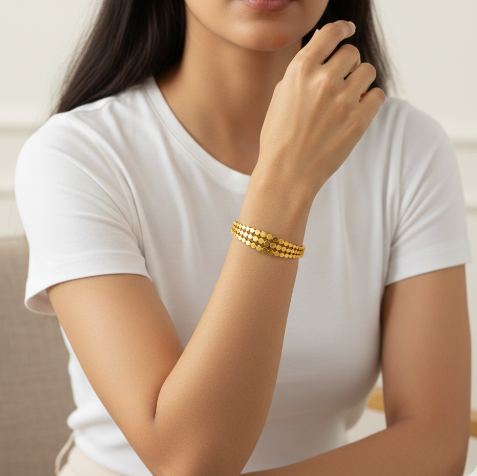 Woman wearing a gold bracelet on her wrist, dressed in a white t-shirt.
