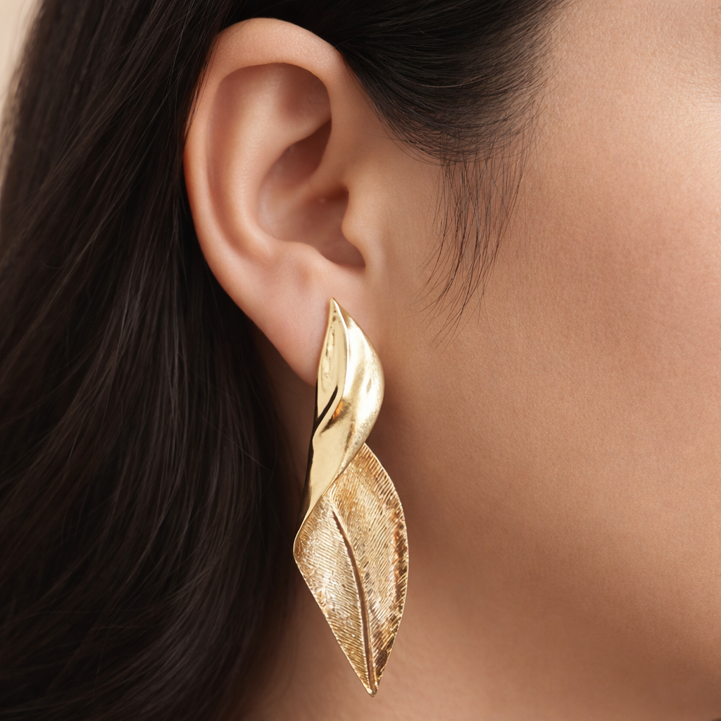 Woman wearing gold plated twisted leaf earrings styled elegantly.