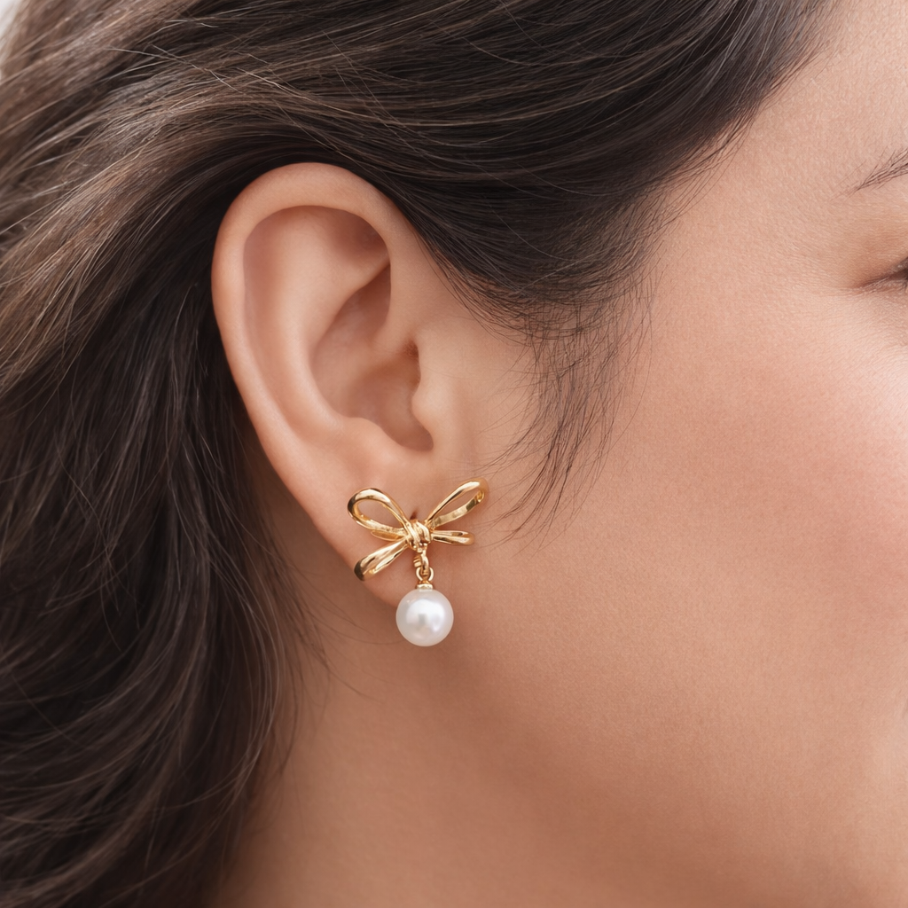 Gold colour geometric looped pearl stud earrings worn by a woman in a minimal everyday look