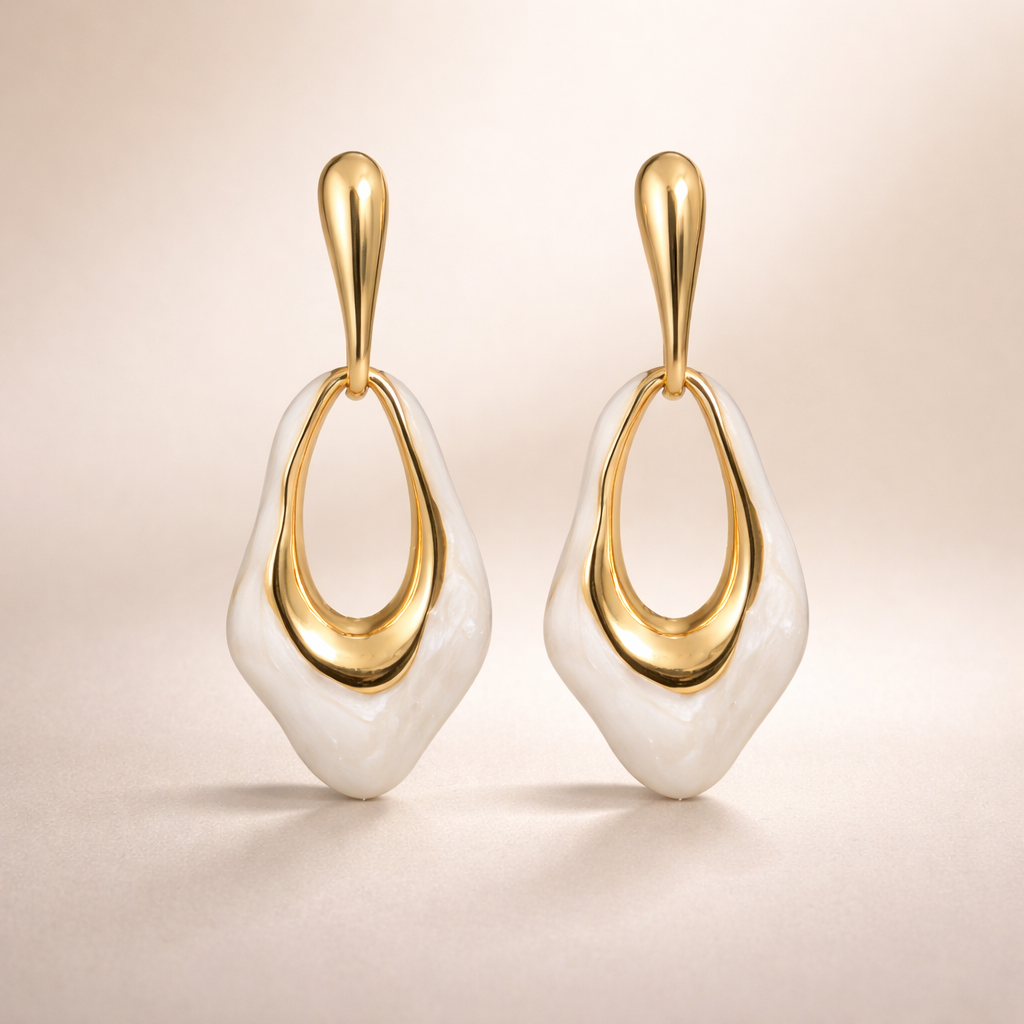 Pair of gold and white earrings on a beige background