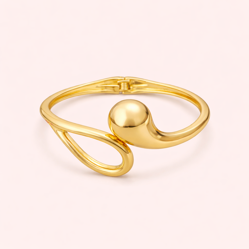 Gold bracelet with a spherical design on a light pink background