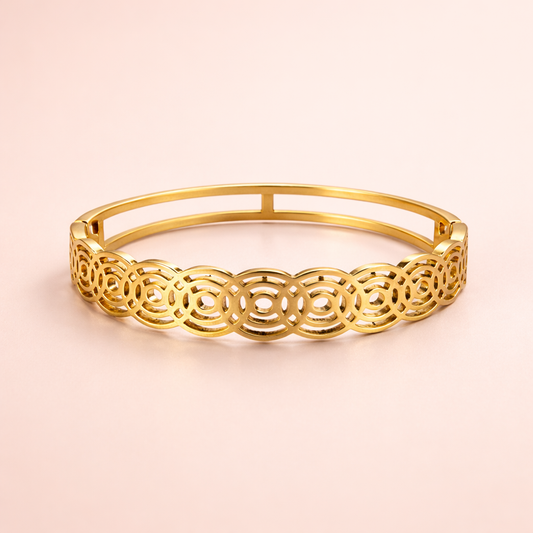 Gold bracelet with intricate design on a light pink background