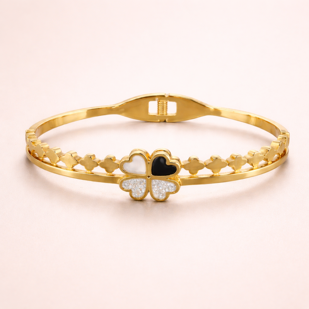 Gold bracelet with a clover-shaped charm on a light pink background