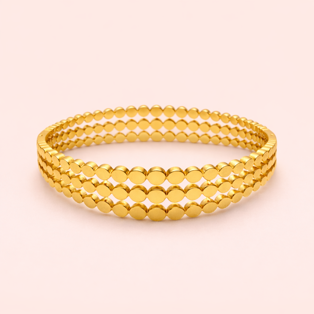 Gold plated triple layer disc band bracelet for women on blush background.