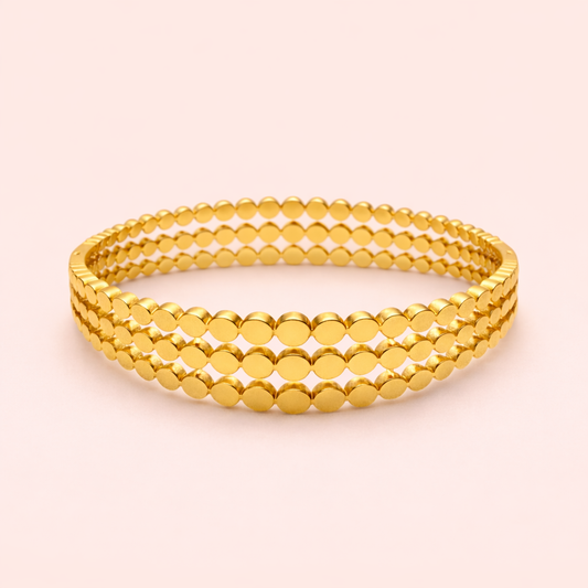 Gold plated triple layer disc band bracelet for women on blush background.