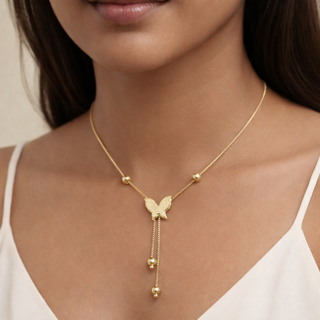 Gold butterfly necklace worn by a model against a neutral background