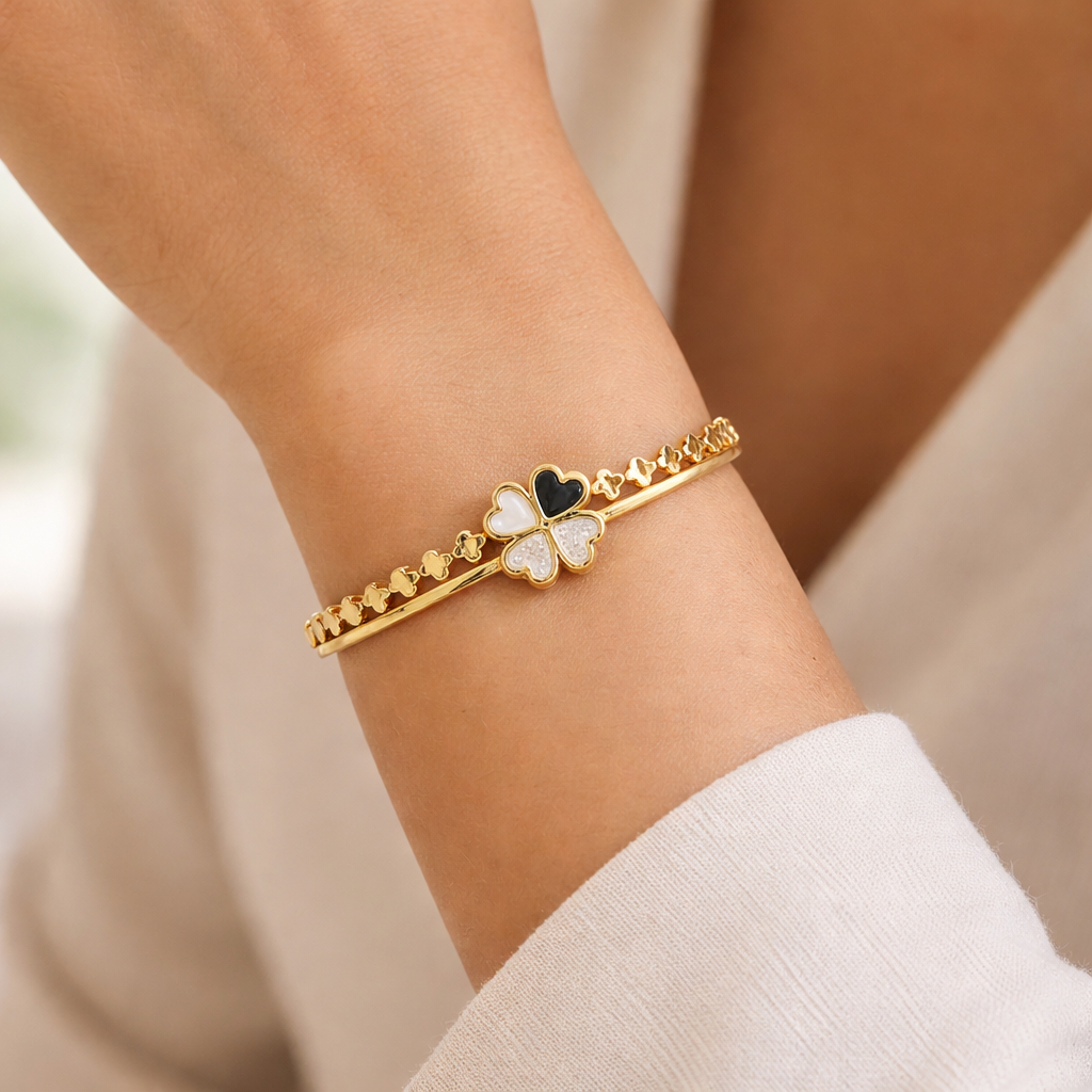 Gold bracelet with heart-shaped charms on a wrist against a neutral background