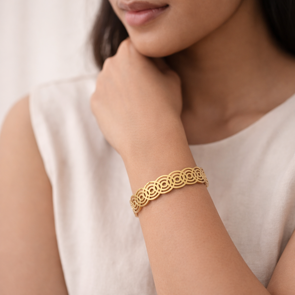 Woman wearing gold plated concentric circle cutwork bangle styled elegantly.