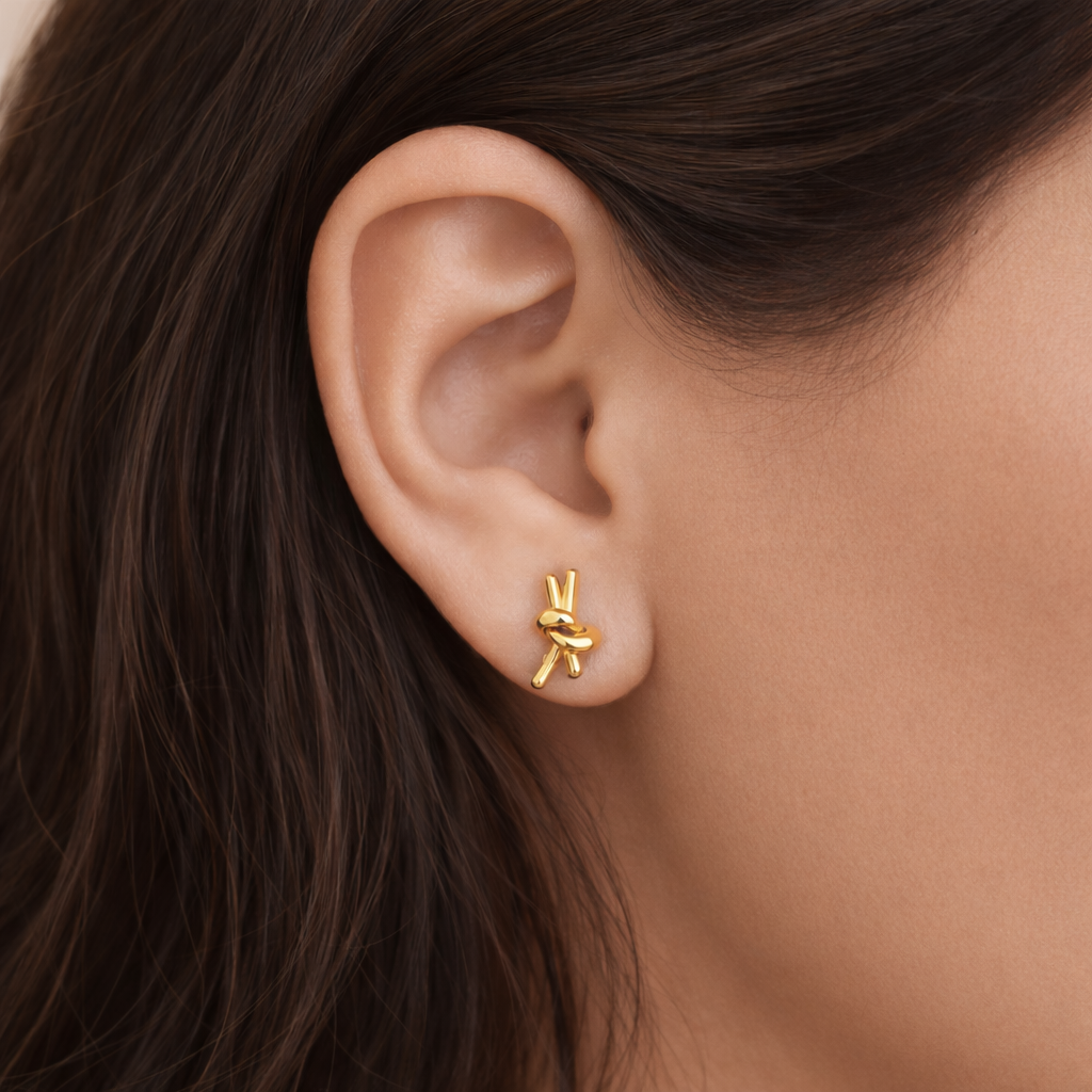 Gold plated knotted stud earrings worn by a woman styled for a minimal everyday elegant look