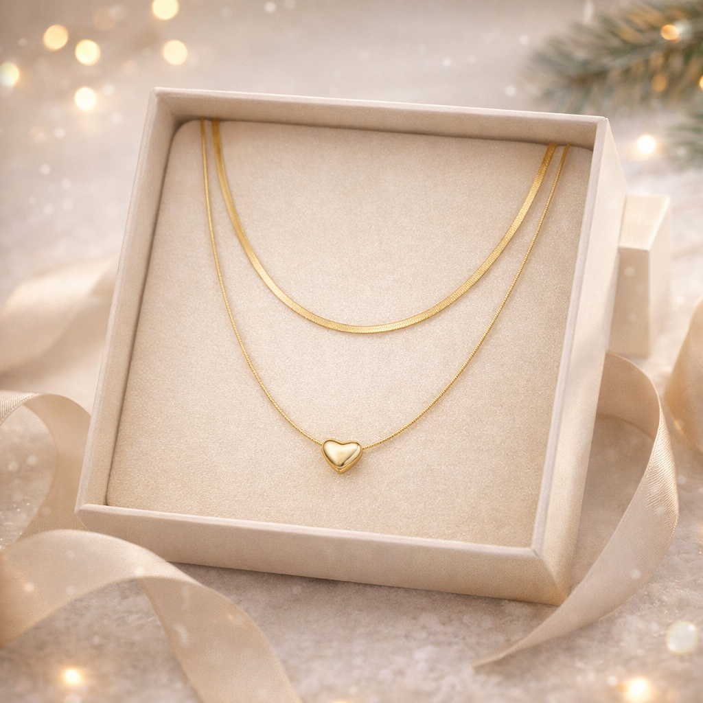 Gold necklace with a heart pendant in a decorative box with ribbons and lights.