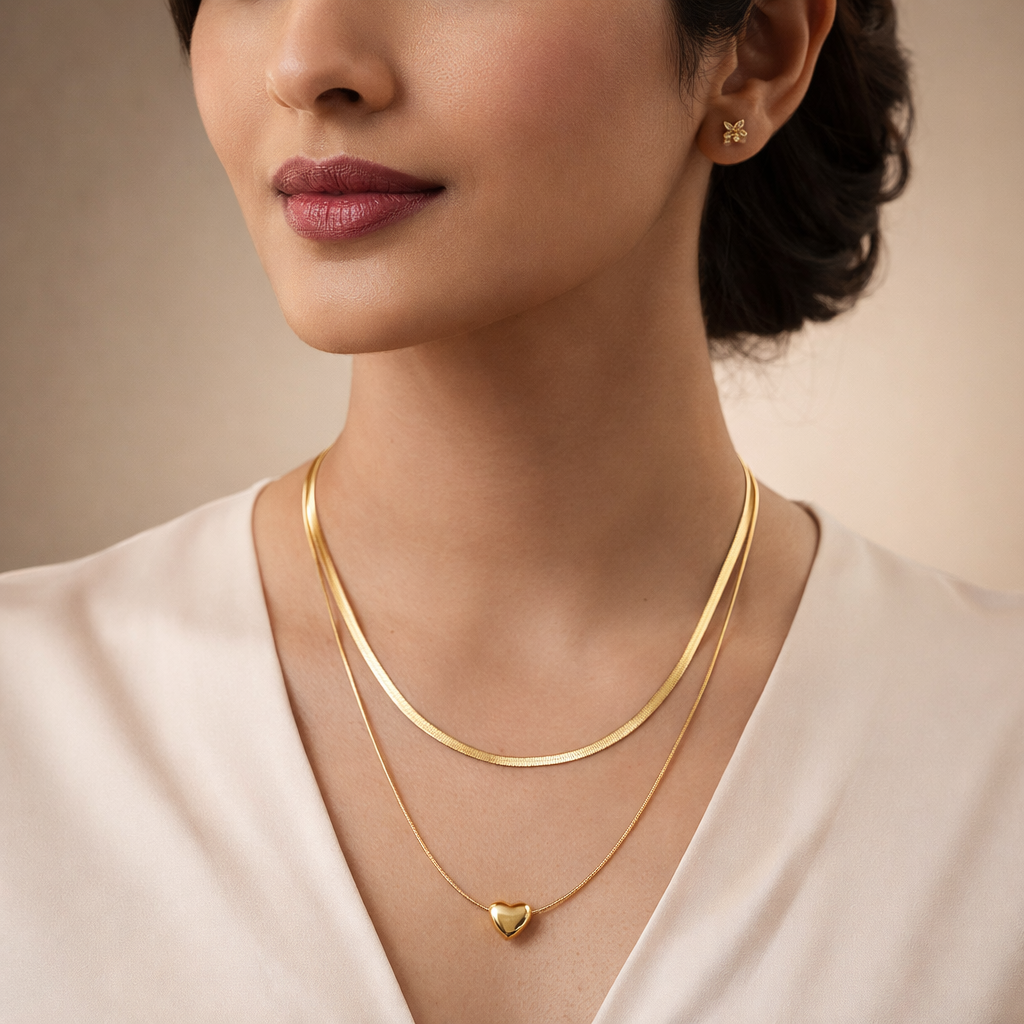 Woman wearing gold necklaces and earrings against a neutral background